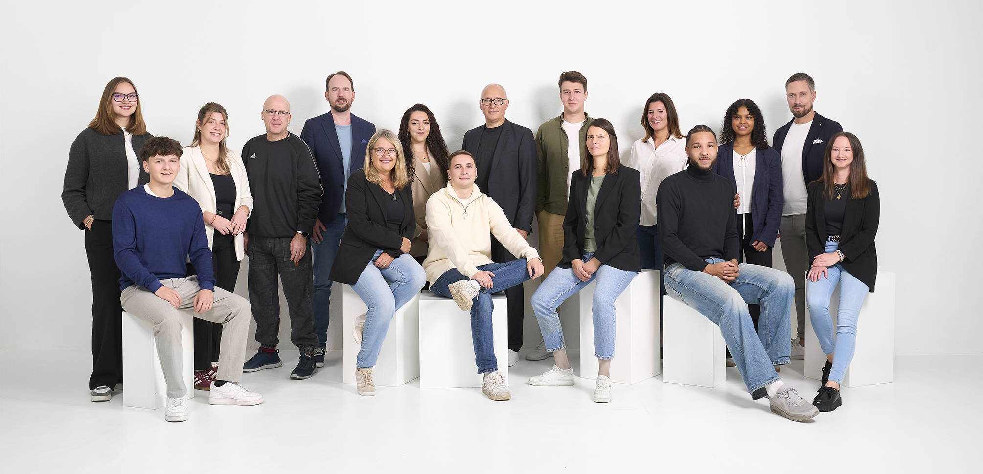 Das ganze Team der Holinger Moll Immobilien AG vor grauem Hintergrund.